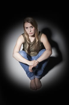 Unhappy Young Woman Sitting In Pool Of Light