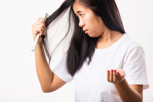 Asian woman weak hair problem her use comb hairbrush brush her hair and showing damaged long loss hair from the brush on hand, studio shot isolated on white background, Medicine health care concept