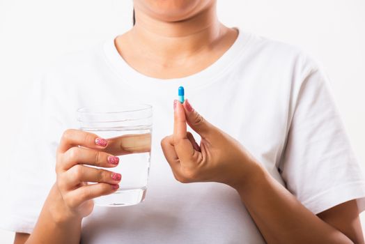 Closeup young Asian woman hold pill drugs in hand ready take medicines with a glass of water, studio shot isolated on white background, Healthcare and medical pharmacy concept