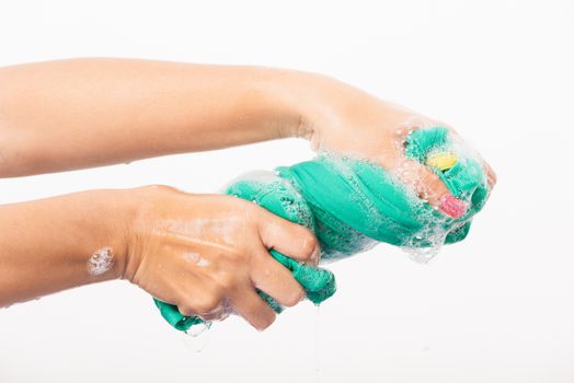 Closeup young Asian woman use hands wash color clothes. Female squeeze wring out wet fabric cloth with detergent have soapy bubble in water, studio shot isolated on white background, laundry concept