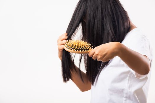 Asian woman unhappy weak hair she shows hairbrush with damaged long loss hair in the comb brush on hand, studio shot isolated on white background, medicine health care concept