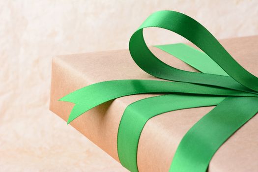Closeup of a plain wrapped Christmas gift with green ribbon and bow. Shallow depth of field only showing part of the present. Horizontal format.