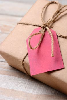 Closeup of a plain wrapped Christmas Present with a red gift tag. The tag is blank. Shallow Depth of field.