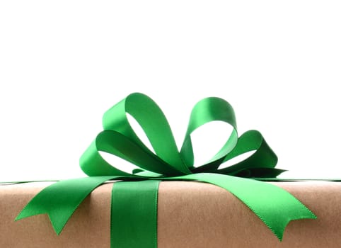 Closeup of a plain wrapped Christmas gift with green ribbon and bow. Only the top portion of the present is shown against a white background. Horizontal format.