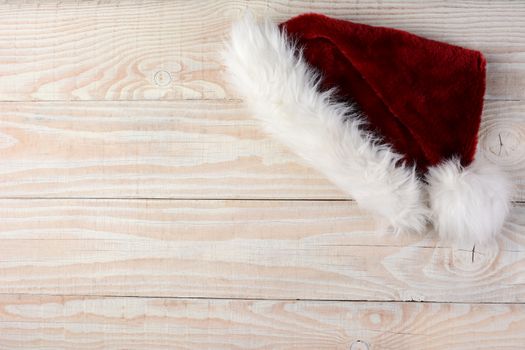 High angle shot of a Santa Hat on a white wood table. Horizontal format with the hat in the upper right corner leaving room for your copy.
