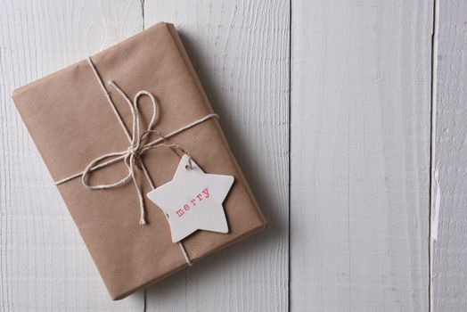 Top view of a group of a paper wrapped Christmas presents with a wood gift tag stamped with the word Merry.