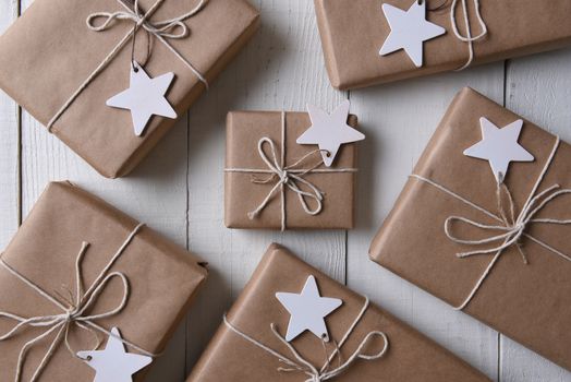 Top view of a group of plain paper wrapped Christmas presents with blank wood star gift tags.