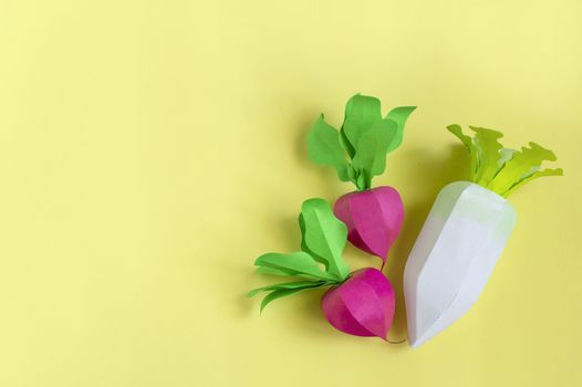 Colorful radish and daikon made from paper on yellow background. Real volumetric handmade paper objects. Paper art and craft