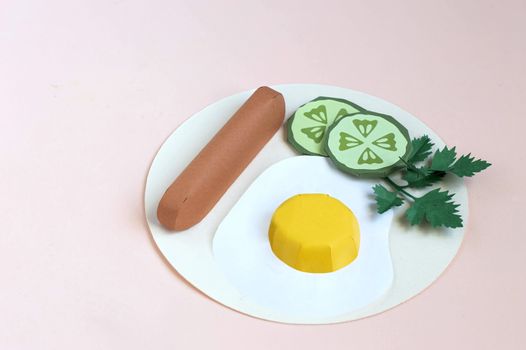 Paper fried eggs with sausage, cucumber slices and parsley on plate. Real volumetric handmade paper objects. Paper art and craft