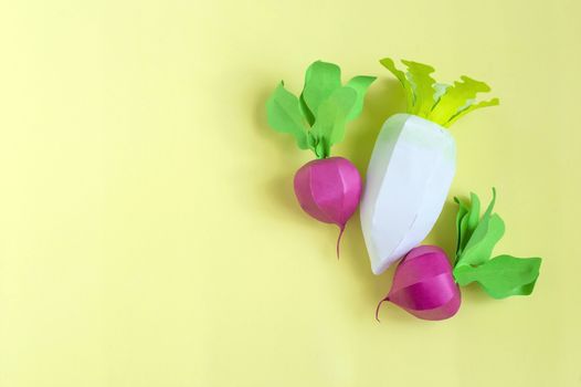 Colorful radish and daikon made from paper on yellow background. Real volumetric handmade paper objects. Paper art and craft