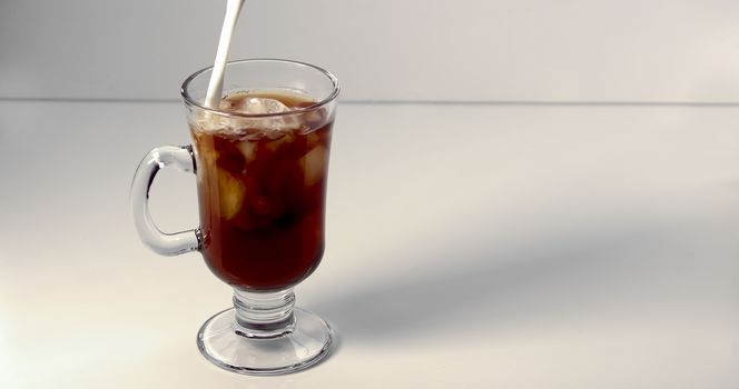 Pouring cream on an ice coffee cup on a white background