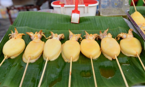 Squid carapace, skewers placed on a green banana leaf for sale