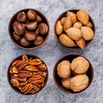 Whole almonds,whole walnuts ,whole hazelnut and pecan nuts in wooden bowl setup with stone background.  Selective focus depth of field.