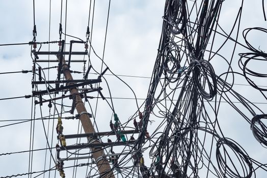 Telephone pole and chaotic mess of wires against sky in China