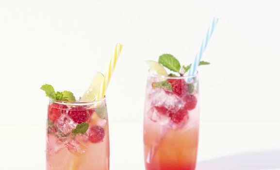 iced red raspberry punch cocktail with lime in glass on white background. summer drink.