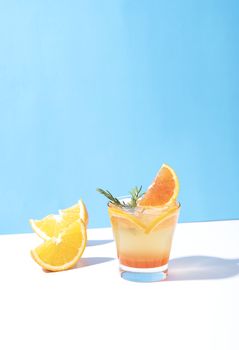 Cold and refreshing orange punch cocktail with orange slice on blue background. summer drink.