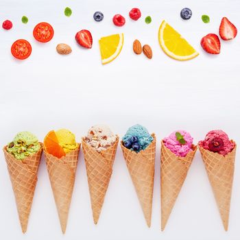 Various of ice cream flavor in cones blueberry ,strawberry ,pistachio ,almond ,orange and cherry setup on white wooden background . Summer and Sweet menu concept.