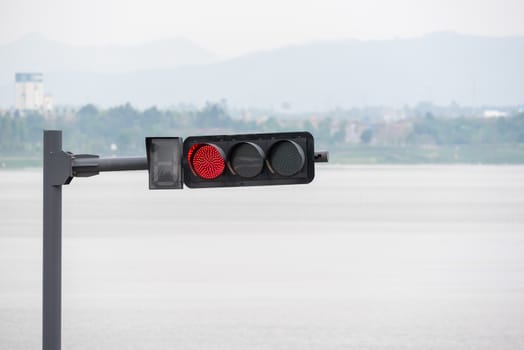 Red traffic light with a lake and mountains in the background