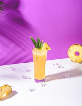 iced pineapple punch cocktail in glass on pink background. summer drink.