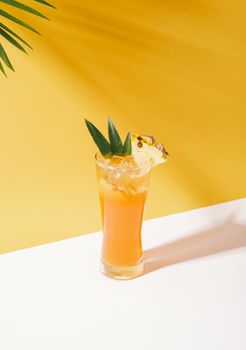 iced pineapple punch cocktail in glass on orange background. summer drink.