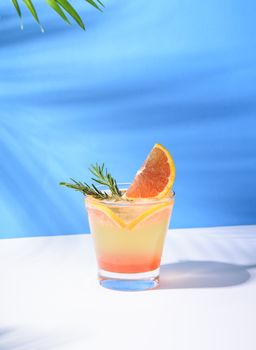 Cold and refreshing orange punch cocktail with orange slice on blue background. summer drink.