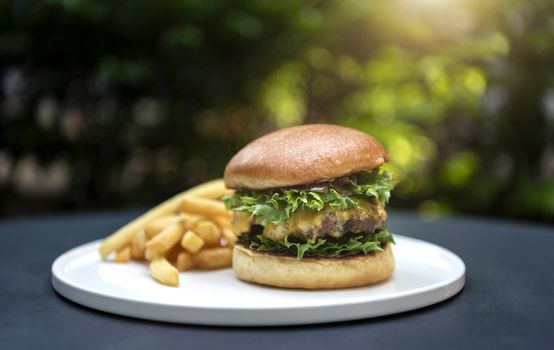 beef burger and french fries on table with sunlight on black table background.