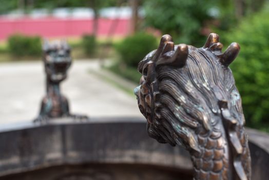 Selective focus on a dragon head decoration on a bronze incense burner in a chinese temple