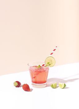 iced strawberry punch cocktail in glass with lime on color background. summer drink.