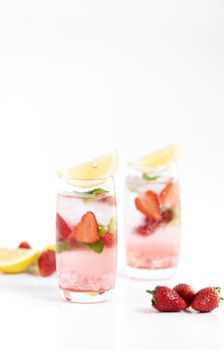 iced strawberry punch cocktail in glass with lemon on white background. summer drink.