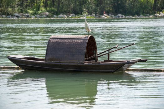 Little egret on a chinese traditional fishing boat on a lake, HuanHuanXi park, Chengdu, China