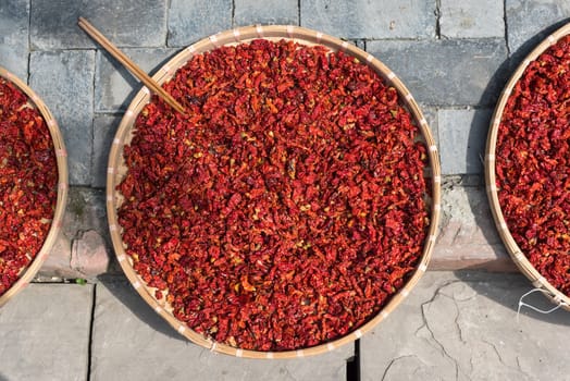 Red chili pepper drying on plates on the ground in China