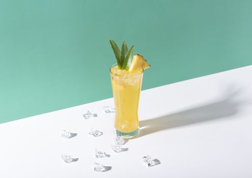 iced pineapple punch cocktail in glass on color background. summer drink.