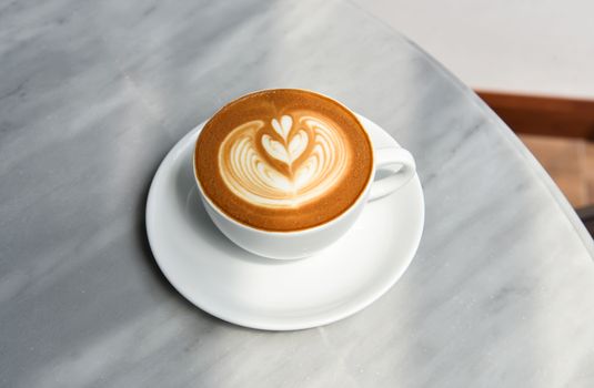 latte or Cappuccino with frothy foam, coffee cup top view on table in cafe.