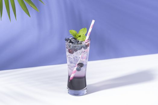 Cold and refreshing  blueberry punch cocktail with mint on purple background. summer drink