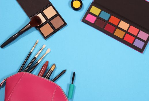 Cosmetics and Brushes on textured blue paper background