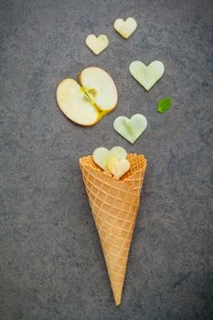 Apple slice in waffle cones and heart shape of apple setup on dark stone background . Valentine 's day and Sweet menu concept.