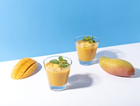 Fresh mango smoothie and ripe mango slice on color background. summer drink.