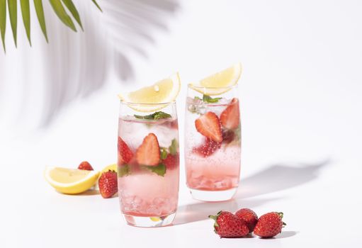 iced strawberry punch cocktail in glass with lemon on white background. summer drink.