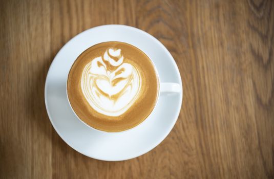 latte or Cappuccino with frothy foam, coffee cup top view on wood table in cafe.