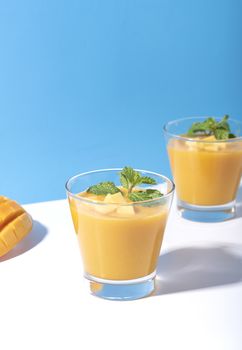 Fresh mango smoothie and ripe mango slice on color background. summer drink.