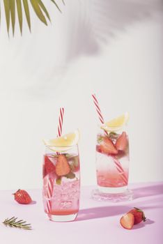 iced strawberry punch cocktail in glass with lemon on white background. summer drink.