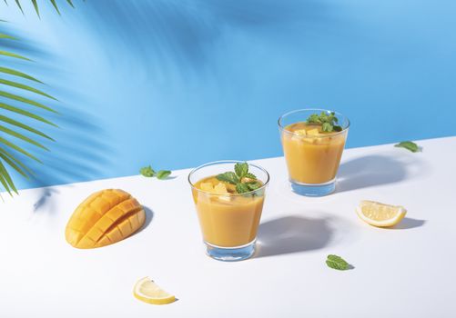 Fresh mango smoothie and ripe mango slice on color background. summer drink.