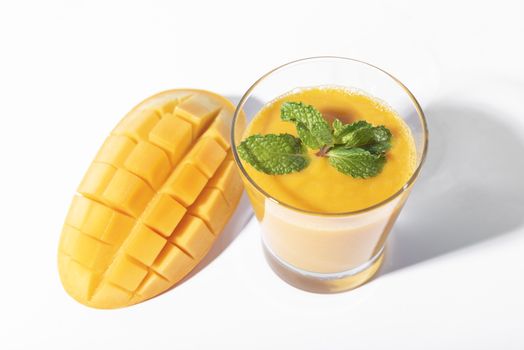 Fresh mango smoothie and ripe mango slice on white background. summer drink.