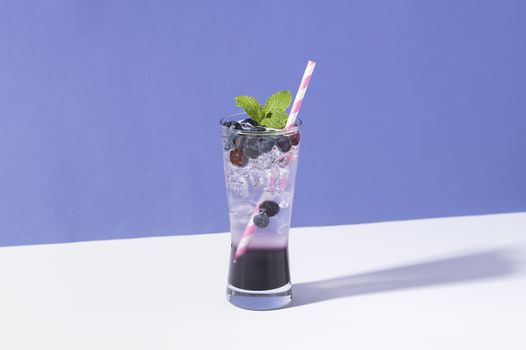 Cold and refreshing  blueberry punch cocktail with mint on purple background. summer drink