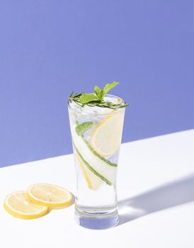 Mojito cocktail with lemon and mint in glass on blue background. summer drink.