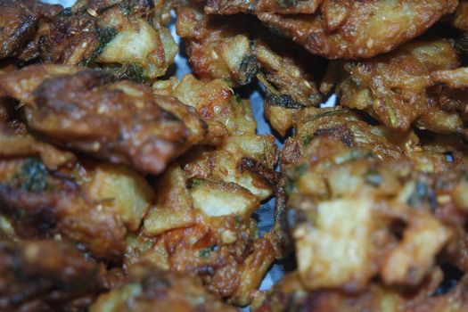 close-up view with selective focus of crispy basin pakora/pakoda or patties are popular indian or pakistani street food snack, served with green salad and sauce. Selective focus of