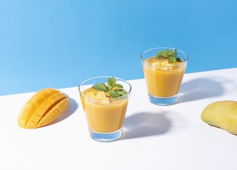 Fresh mango smoothie and ripe mango slice on color background. summer drink.