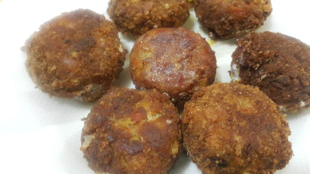 Delicious spicy fried round kebab served in a white ceramic plate on wooden floor