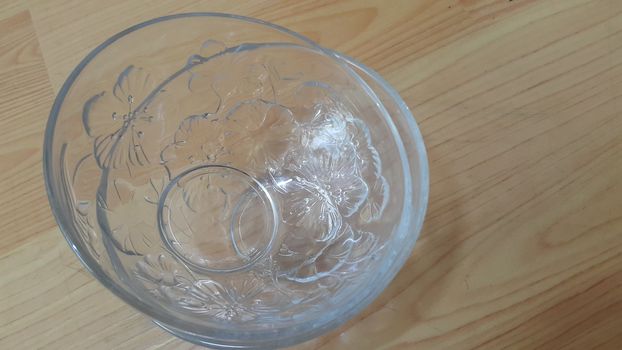 Top view of empty white glass bowls on a wooden floor. Glass bowl with flowers made on its wall