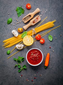 Italian food and menu concept. Spaghetti with ingredients sweet basil ,tomato ,garlic peppercorn and champignon on dark background flat lay and copy space.